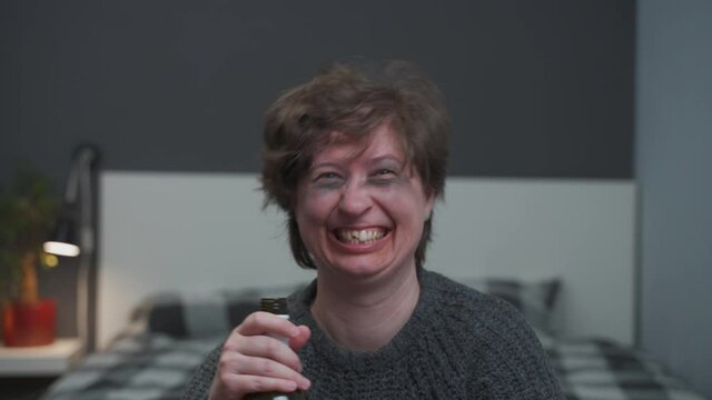 Problem of alcoholism in women at young age. Caucasian young woman with bottle independent of alcohol, has injuries on face and lost teeth from unhealthy lifestyle. Husband calms down his drunk wife