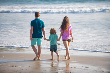 Happy family holidays. Joyful father, mother, baby son walk of sea sand beach. Active parents and...