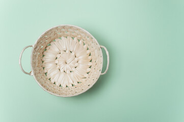 Round empty wicker straw basket with handles on light green background. View from above. Decorative interior items. Copy space