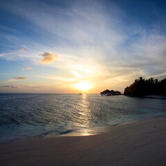 Sunrise early in the morning on the beach of Embudu in the Maldives with the silhoutte of bungalows over the ocean.