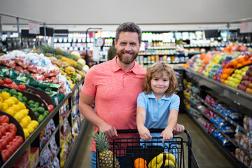 Father and son buy fresh vegetable in grocery store. Family in shop.