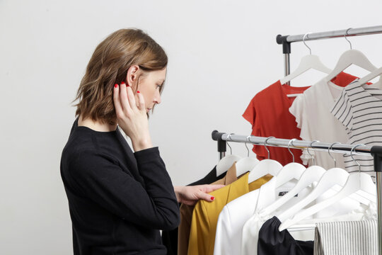 Beautiful Young Woman Near Rack With Clothes Making Choice What To Wear