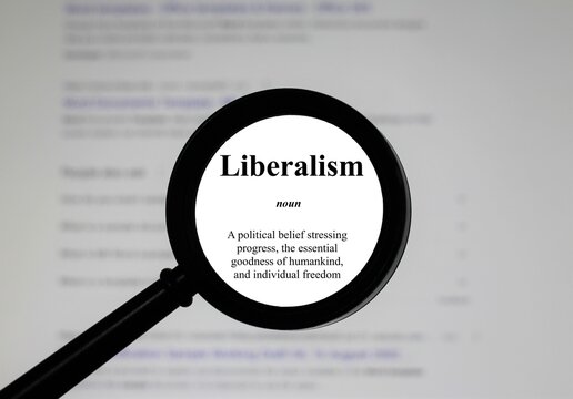 Selective focus on word liberalism, word in a dictionary. Close up of an English dictionary page with the word liberalism