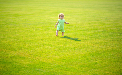 Adorable baby crawling on green grass outdoors.