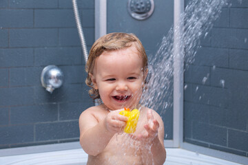 Little baby child is washing her hair in bath. Child in shower.
