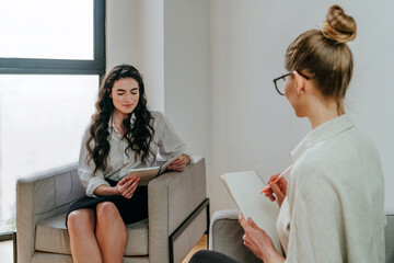 Young woman coach or trainer interviewing her trainee indoor