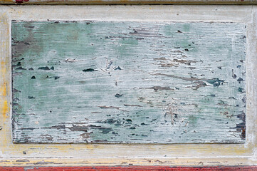 Blue and yellow paint peeling off of old weathered aged wooden plank