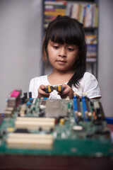 Little asian girl studying computer hardware 