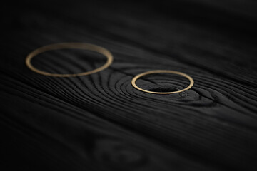 Black wood texture background decorated with golden rings. Selective focus