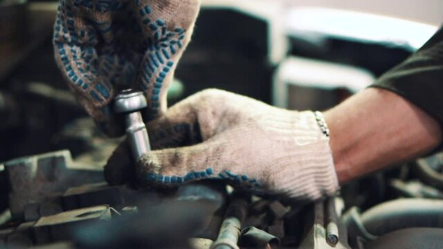 Master in gloves unscrews the bolt with a silver key close up