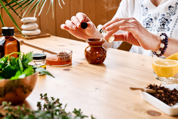 Woman prepares aromatherapy session at the table with essential oil diffuser medical herbs, different types of oils and essences. Aromatherapy and alternative medicine concept. Natural remedies.