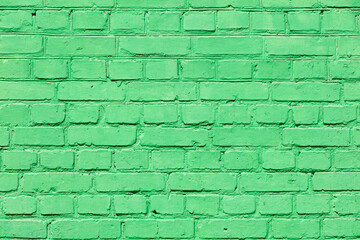 A very old brick wall completely painted with green paint.
