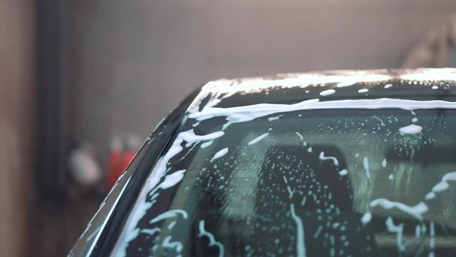 Black car sedan after washing in foam from side and back angles