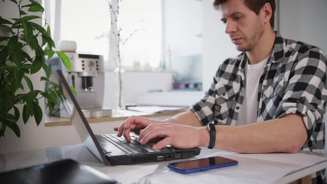 Man works at home office with laptop and documents