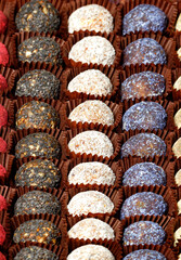 Sweets, handmade energy balls filled with various seeds, in craft paper baskets, lie in even rows.