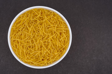 Vermicelli in a white glass bowl. Top view photo of vermicelli on dark grey background. Isolated close up photo