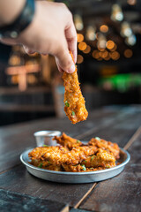 Deliciosas tiras de pechuga de pollo empanizadas fritas y crujientes con salsa barbacoa con mano