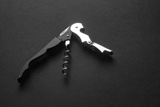 Opened sommelier knife with corkscrew and bottle opener, professional waiter knife, on black background
