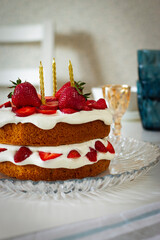 sponge cake with strawberry  with three candles on table 
