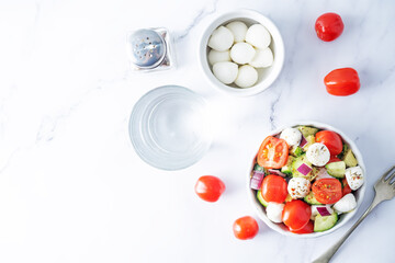 Mozzarella cucumber tomato red onion salad in a white bowl