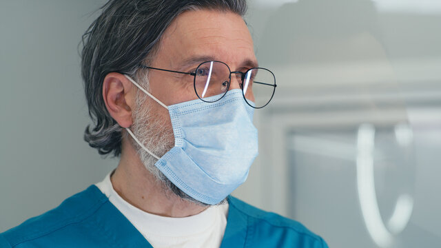 Mature Doctor In Mask Speaking With Patient On Reception In Medical Center