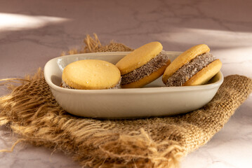 Deliciosos alfajores de maicena rellenos de dulce de leche y espolvoreados con coco rallado, a luz de la mañana.