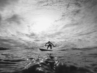 Surfer riding a wave on a cloudy day. Black and white ocean