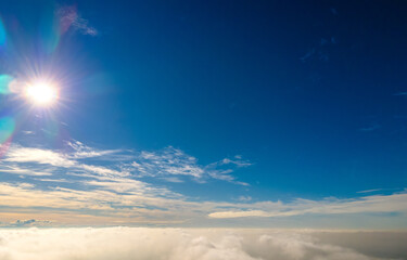 Aerial view from above of white puffy clouds in bright sunny day.