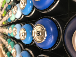 Rows of color paint spray cans placed on a black wall. Abstract colour palette