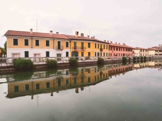 Picturesque colorful houses in Gaggiano, reflected in the navigable canal called Naviglio Grande, near Milan.Lombardy, Italy.