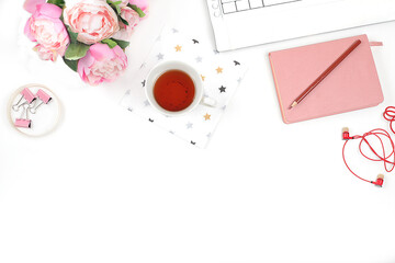 Modern woman working desk, home office. Computer, a cup of tea and spring flowers on a light table. Business minimal concept, home comfort, top view, flat lay, place for text,