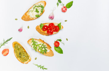 Bruschetta with dried tomatoes, pesto sauce, ricotta, arugula and micro-greens. On a white background, above the head, with ingredients for cooking.