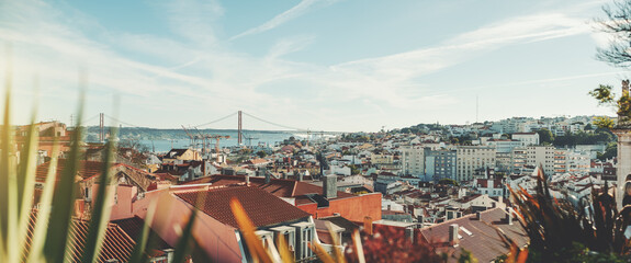 Panoramic shot of a sunny Lisbon cityscape from the high above; the panorama of Lisbon urban landscape with plenty of antique and modern houses and a suspension bridge over Tagus river in a background - obrazy, fototapety, plakaty