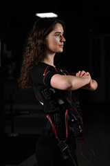 Fototapeta na wymiar Girl in EMS suit in gym. Sport training in electrical muscle stimulation suit. Making physical exercises