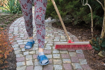 Sweeping a granite paving path in the spring garden 