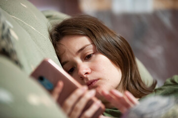 Sad girl lying in bed with phone