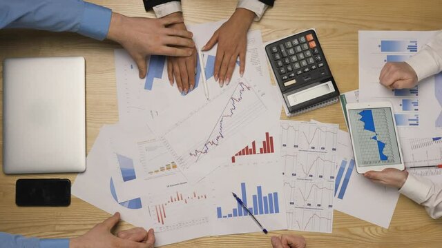 Top view of a young business team shaking hands rejoicing in a good deal. A group of men and a woman cheer each other on before a difficult meeting or presentation. Close up. Slow motion.