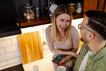 Young Caucasian smiling couple is having fun at kitchen.