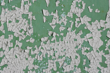 Peeling paint on the wall. Old concrete wall with cracked flaking paint. Weathered rough painted surface with patterns of cracks and peeling. High resolution texture for background and design. Closeup