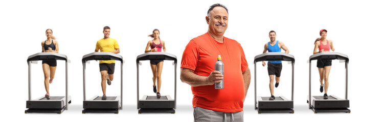 Mature man in sports clothing holding a bottle and people running on treadmills