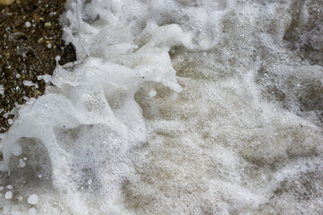 pebble stones on the sea beach, the rolling waves of the sea with foam