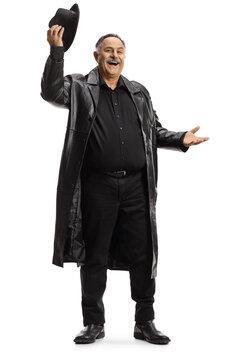 Full length portrait of a mature man in a trench coat lifting his hat