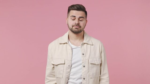 Fun confused shy shamed young man 20s wear light jacket white t-shirt look camera spreading hands aside say oops ouch oh omg i am so sorry isolated on pastel pink wall color background studio portrait