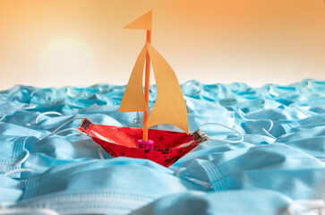 Sailing boat on open sea created of surgical masks