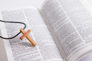 Close up wooden cross on open bible page