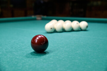 dark billiard ball on the table against the background of white billiard balls