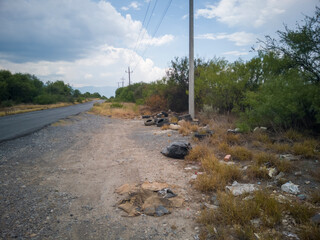 camino rural con basura en las orillas, con cielo nublado