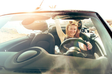 Young women drive a car on the beach.