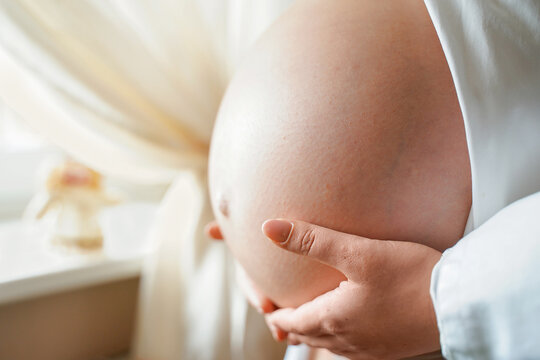 Side view pregnant woman with big belly advanced pregnancy in hands. Healthy pregnancy. light mood photo, copy space