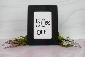 50% off sign in black wood picture frame with pink white greenery 